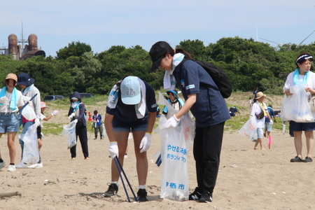 写真:海岸でゴミ拾いをする親子
