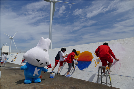 写真：岸壁の1000人画廊に絵を描く学生とカミスココくん