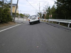 写真：道路が隆起し自動車が傾いている様子