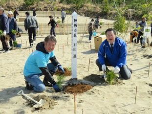 写真：植樹した苗と一緒に記念撮影をする石田市長