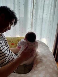 写真：娘がゲップするのを促すパパ