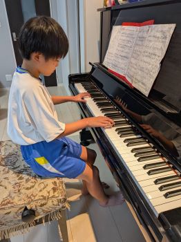 写真:ピアノの演奏を練習する少年