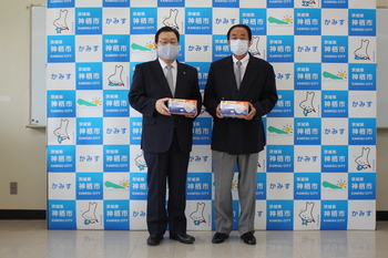 写真：寄付されたマスクを持ち、株式会社鹿島冷熱の1名と記念撮影
