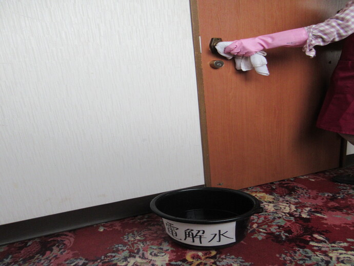 写真:ドアノブを拭くようす