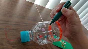 写真：ペットボトルに水性ペンで模様を描いている様子
