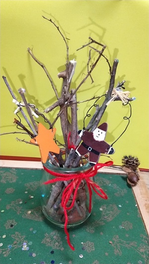 写真：赤色の毛糸やサンタクロースの人形を木の枝に飾り付けたようす
