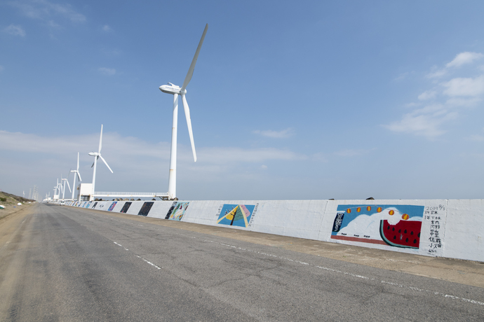 写真：絵が描かれた護岸壁と立ち並ぶ風車