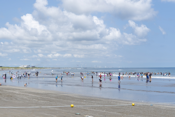 写真：波打ち際で遊ぶたくさんの海水浴客
