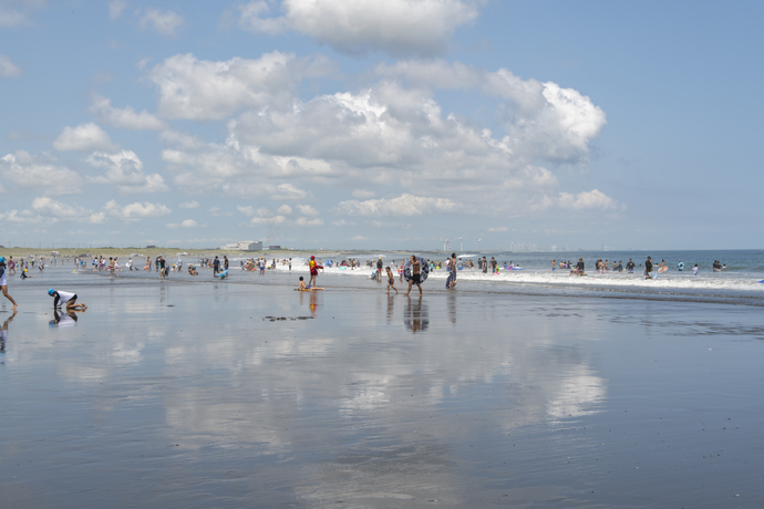 写真：白い雲が写るほどきれいな海と海水浴客