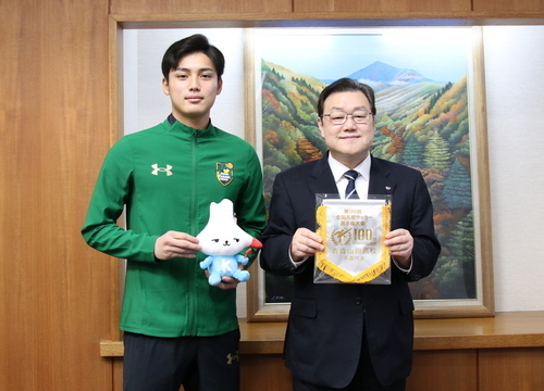 写真:2月17日撮影の訪問者とチームペナントを持つ石田市長