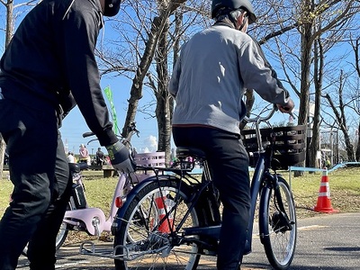 写真：電動アシスト自転車に体験乗車する人とサポートする人