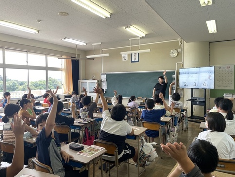 写真：教室でスポーツ栄養士さんの問いかけに手を挙げて答える子どもたち