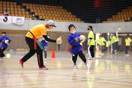 写真：ラグビーボールを持って走る参加者を追いかけるスペシャルゲストの加藤優さん
