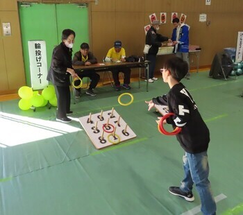 写真：子どもが輪投げをしているのを見守るシニア