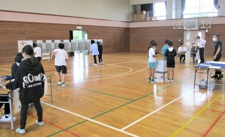 写真：体育館に設置された投票所で児童が模擬投票する様子