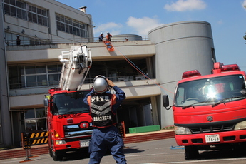 写真:消防団員が屋上から地上へむけて救助訓練をおこなっている様子