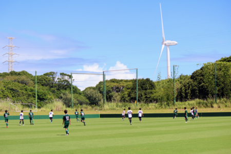 写真：風車がみえるサッカー場のもとでおこなわれたフレンドリーマッチ