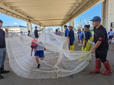 写真：漁網を使って網くぐりをする小学生