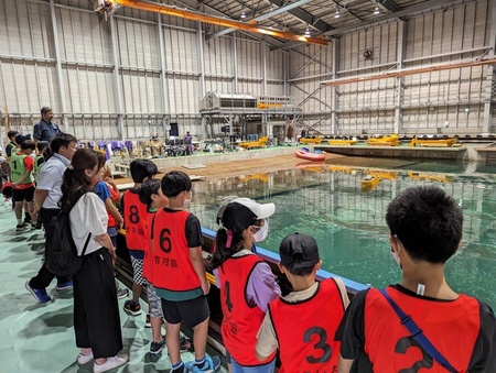 写真:水産技術研究所の実験用プールにて、模型実験をみつめる子どもたち