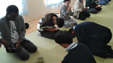 写真：畳の上で提供されたお茶を、正座した参加者が受け取る様子