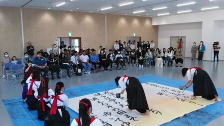 写真：袴姿の書道パフォーマンスを参加者が見つめる様子