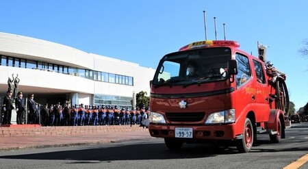 写真：消防車両を敬礼しながら見送る消防関係者たち