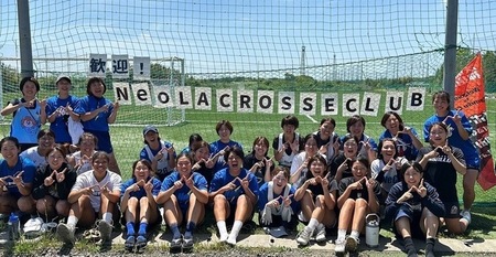 写真：歓迎看板の前で記念撮影する「NeO LACROSSE CLUB」の皆さん