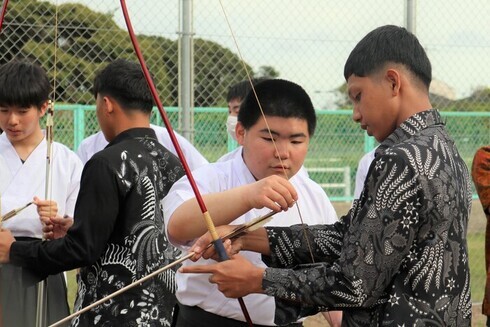 写真：高校生から弓を射る方法を教わる技能実習生