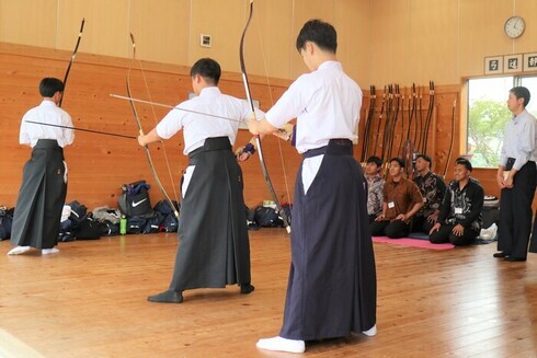 写真：高校生が実演するようすを正座しながら見届ける技能実習生達