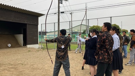 写真：弓道部員に教わりながら弓を引く練習をする技能実習生