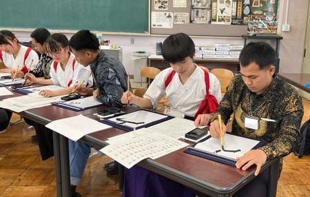 写真:高校生に教えてもらい書道体験をする技能実習生