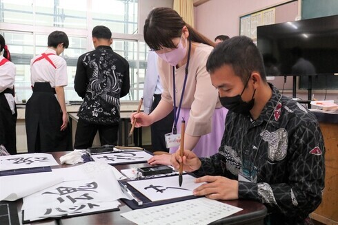 写真：講師に教わりながら書道を体験する技能実習生
