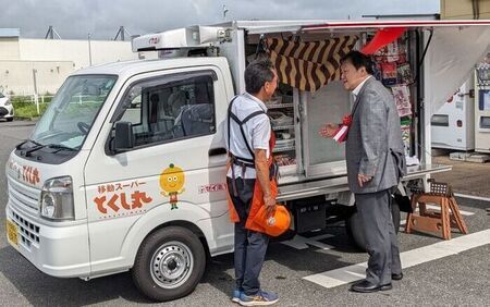 写真：「移動スーパーとくし丸」の前でサービスの説明を受ける市長
