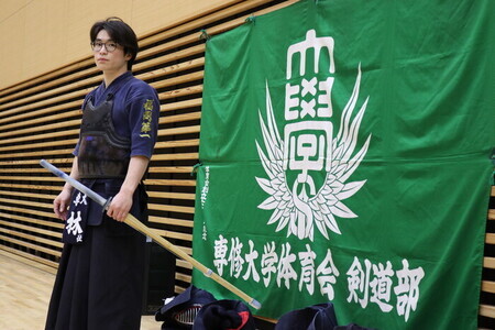 写真:専修大学体育会剣道部の垂れ幕の前で一枚。地域交流会で指揮を執る主将