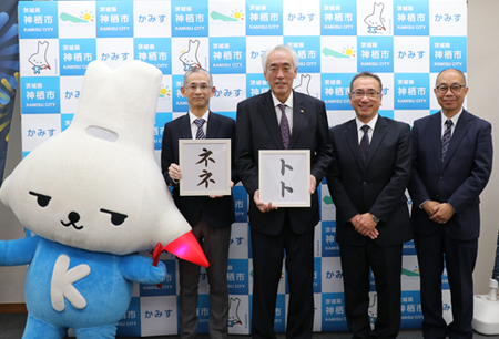 写真：「ネネ」「トト」という文字が書かれたパネルを持つ木内市長と株式会社クラレの皆さん、カミスココくんとともに記念撮影