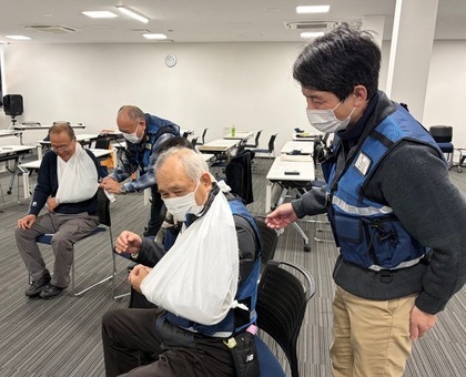 写真：2人1組で三角巾の固定方法を実践する防災士