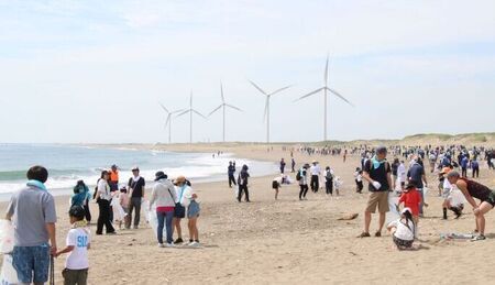写真：海岸清掃当日の様子。日川浜海岸にてごみ拾いをする参加者達