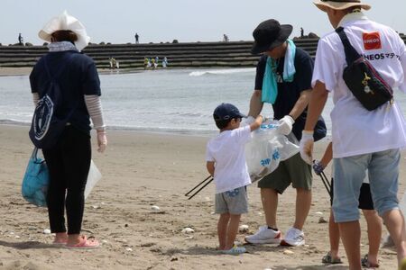 写真：波打ち際でごみを拾っている親子