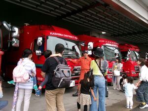 写真：消防署の職員から消防車の説明を聞いている親子