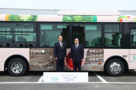 写真:2025年9月10日撮影。寄付者と市長が扶桑化学工業株式会社の広告がラッピングされたバスの前で記念撮影。