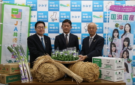 写真：2025年10月28日撮影。ピーマン・長ネギ・米俵など、贈呈された食材を前に記念撮影