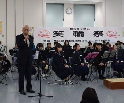 写真:2025年12月7日撮影。吹奏楽部の生徒の横で挨拶をする市長