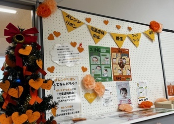 写真：オレンジリボンの活動について紹介しているパネルとハート型メッセージカードが飾られたツリー