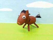 写真:空と草原をイメージした背景とまゆで作った茶色の馬