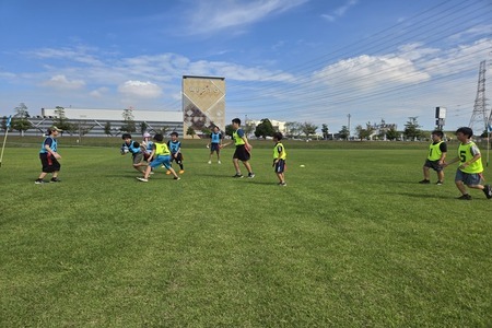 写真：ラグビーボールを持って走る子どもを追いかける子どもたち