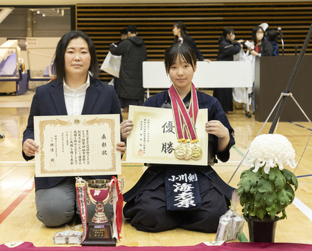 写真：左から、引率者の女性と、金メダルを首からさげ賞状を手にする海老原選手