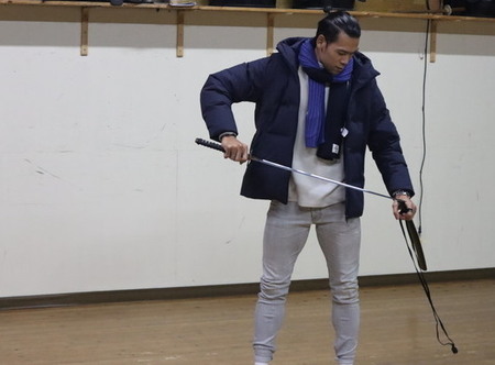 写真:剣道体験で、参加者が鞘から剣を抜くようす