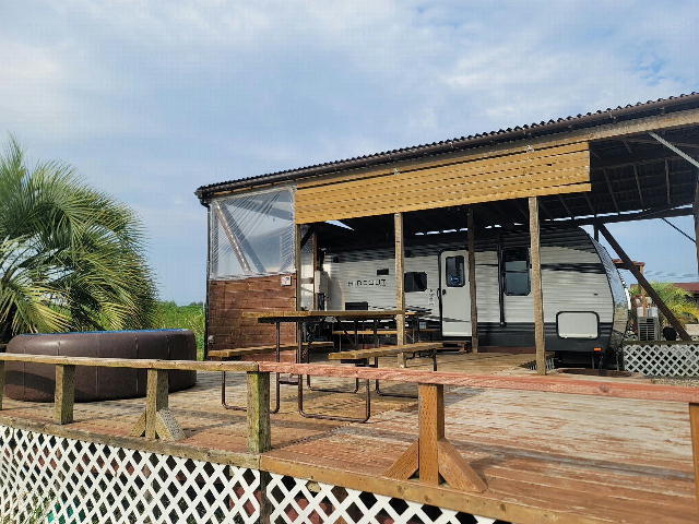 写真：ウッドデッキにテーブル・椅子・トレーラーハウスを完備したコテージエリア