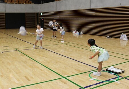 写真：2人でおこなうスポーツで、片方の人が紙ヒコーキを投げ、もう片方の人が虫取り網で紙ヒコーキをキャッチする