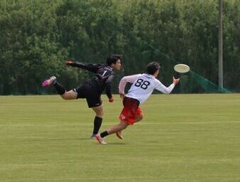 写真：二人の選手がフライングディスクを懸命に追いかけているようす